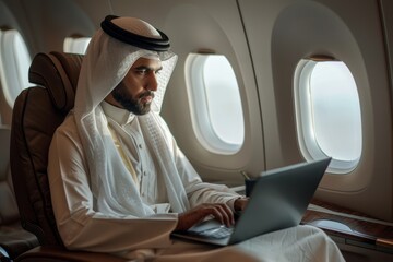 muslim businessman in white traditional outfit working on laptopin plane during business trip, Generative AI 