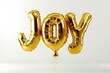 © Lal - A vibrant golden balloon emblazoned with the word 'Joy' in elegant script letters, against a pristine white backdrop.