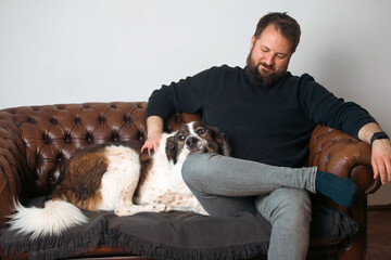 Wall Mural - Man sitting on the sofa with his dog.