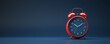© Fokasu Art - A classic alarm clock in red is isolated on a navy blue background, with bells on top and ticking hands visible