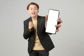 portrait of happy asian businessman wearing suit holding mobile phone and showing blank screen  on isolated background