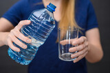 Fototapeta  - Woda gazowana w plastikowej butelce szklanka w dłoni, nalewać wodę zbliżenie