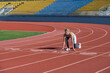 © Yevhen - Confident young sportswoman getting ready to run a distance at the stadium. Runner woman in sportwear getting ready to run sprint at low start on stadium track with red coated