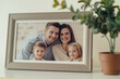 © Enigma - Framed photograph of a happy family with two parents and two children, displayed on a wooden table beside a potted plant, symbolizing home warmth and cherished memories