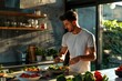 © JuLady_studio - A fit, handsome young man is seen making breakfast from healthy food and vegetables in his kitchen at home. The photo highlights a commitment to wellness and home-cooked meals.