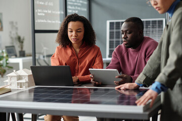 Leinwandbilder - Two young African American employees with laptop and tablet preparing new business project while sitting by workplace in office