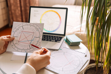an astrologer draws with a pencil on a natal chart.