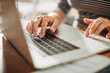© Marko Geber - Close-up of woman's hands typing on laptop keyboard