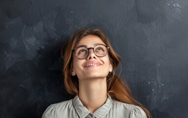 Joyful businesswoman in glasses looking up with a hopeful smile.