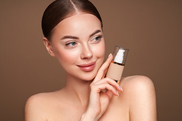 Wall Mural - portrait beautiful young woman with clean fresh skin. model with foundation makeup bottle. cosmetolo