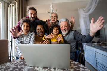 Wall Mural - Extended multiethnic family together at home during video call. People happiness technology concept