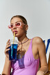 © LIGHTFIELD STUDIOS - Trendy blonde woman in chic pink swimsuit enjoying a refreshing drink.