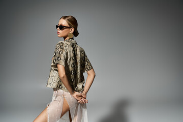 Wall Mural - Stylish woman sporting sunglasses and a trendy snakeskin shirt.