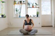 © Johnér - Pregnant young woman touching abdomen while sitting on exercise mat at home