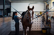 © Johnér - Side view of female animal trainer standing by horse at ranch