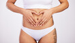 © peopleimages.com - Woman, heart and hands on stomach in studio, diet and weight loss for gut health. Fitness, body wellbeing and abdomen of girl for wellness or digestion, balance and nutrition in white background