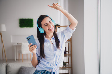 Sticker - Portrait of pretty lady smart phone headphones listen music wear shirt bright interior apartment indoors