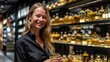 © vefimov - A woman is smiling and holding a glass of liquor in a liquor store. The store is filled with various bottles of liquor, and the woman seems to be enjoying her time there