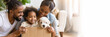 © Dina Photo Stories - Relocation, renovation, delivery service, adopt puppy banner. adorable puppy in a cardboard box and happy afro-American family in background. New home, getting a dog, moving. Copy space