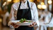 © vetrana - Waitress holding food tray in restaurant, close-up shot in elegant hotel setting