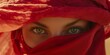 © Asad - Portrait of a woman hiding her face behind red fabric, with only her green eyes visible