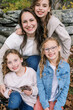 © Serena Burroughs/Stocksy - family portrait of smiling mother being hugged by her daughters