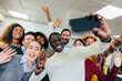 © VICTOR TORRES/Stocksy - Diverse office team capturing a happy moment together with cellphone