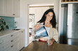 © Nicola Suttle/Stocksy - Smiling woman pouring water from glass filter