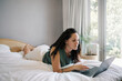 © Nicola Suttle/Stocksy - Relaxed woman using laptop in bedroom