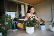 © Nicola Suttle/Stocksy - Young woman practicing house plants gardening on balcony