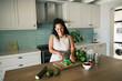 © Nicola Suttle/Stocksy - Smiling housewife cutting celery in kitchen