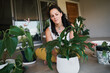 © Nicola Suttle/Stocksy - Focused woman taking care of house plants on balcony