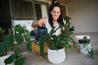 © Nicola Suttle/Stocksy - Cheerful woman watering indoor plants at home