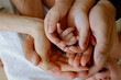 © Olga Murzaeva/Stocksy - dad's and mom's hands hold the baby's hand