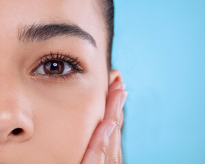 Studio, eye and half portrait of girl with cosmetics, facial skincare and makeup for lashes. Beauty, dermatology and face of woman with mascara, eyebrow and healthy skin wellness on blue background.