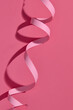 © Marc Tran/Stocksy - Curved pink paper ribbon on a pink background.