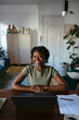 © BONNINSTUDIO/Stocksy - Cheerful woman sitting at table with laptop