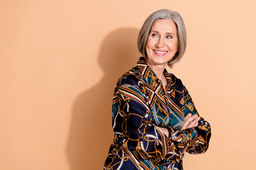 Poster - Portrait of optimistic woman with gray hairstyle wear print blouse arm folded look at sale empty space isolated on beige color background