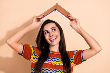 Canvas Print - Photo of nice young woman book above head look empty space wear t-shirt isolated on beige color background