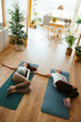 © BONNINSTUDIO/Stocksy - Mother and pregnant daughter doing yoga on mat in living room