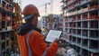 ©  Green Creator - A construction worker wearing a hard hat and safety vest uses a tablet to view building plans while standing at a construction site.