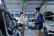 © Jovo Jovanovic/Stocksy - Two car dealership employees having a conversation in the showroom