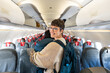 © Alvaro Lavin/Stocksy - Happy traveler in the airplane aisle.