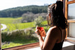 © Alvaro Lavin/Stocksy - Woman drinking coffee by the window.
