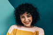 © VICTOR TORRES/Stocksy - Smiling young woman with curly hair on a blue background