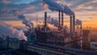 © Samon - Industrial factory with chimneys emitting smoke against a vibrant sunset sky, signifying air pollution and environmental impact.