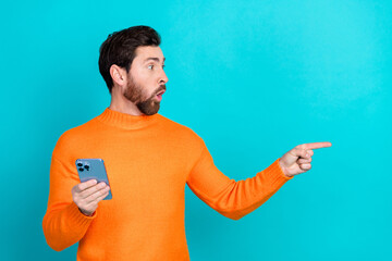 Poster - Photo of attractive excited man wear orange stylish clothes recommend phone empty space isolated on cyan color background