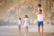 © peopleimages.com - Family, parents and child on shoulders or beach fun on holiday, bonding and walking on sea shore or vacation. People, together and carefree girl or ocean trip for adventure, summer and relaxing