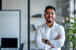 © ramona - smiling young Hispanic business man standing with arms crossed in an office, whiteboard in the background