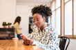 © Guille Faingold/Stocksy - Woman texting  by Smartphone at Office Table